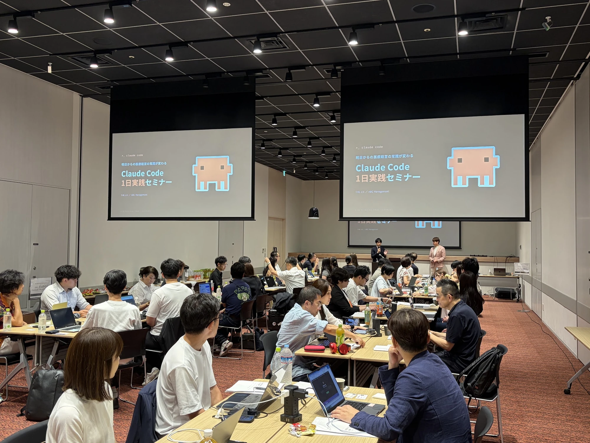 大型スクリーンのある会場で、受講生がパソコンを使って参加する実践セミナー